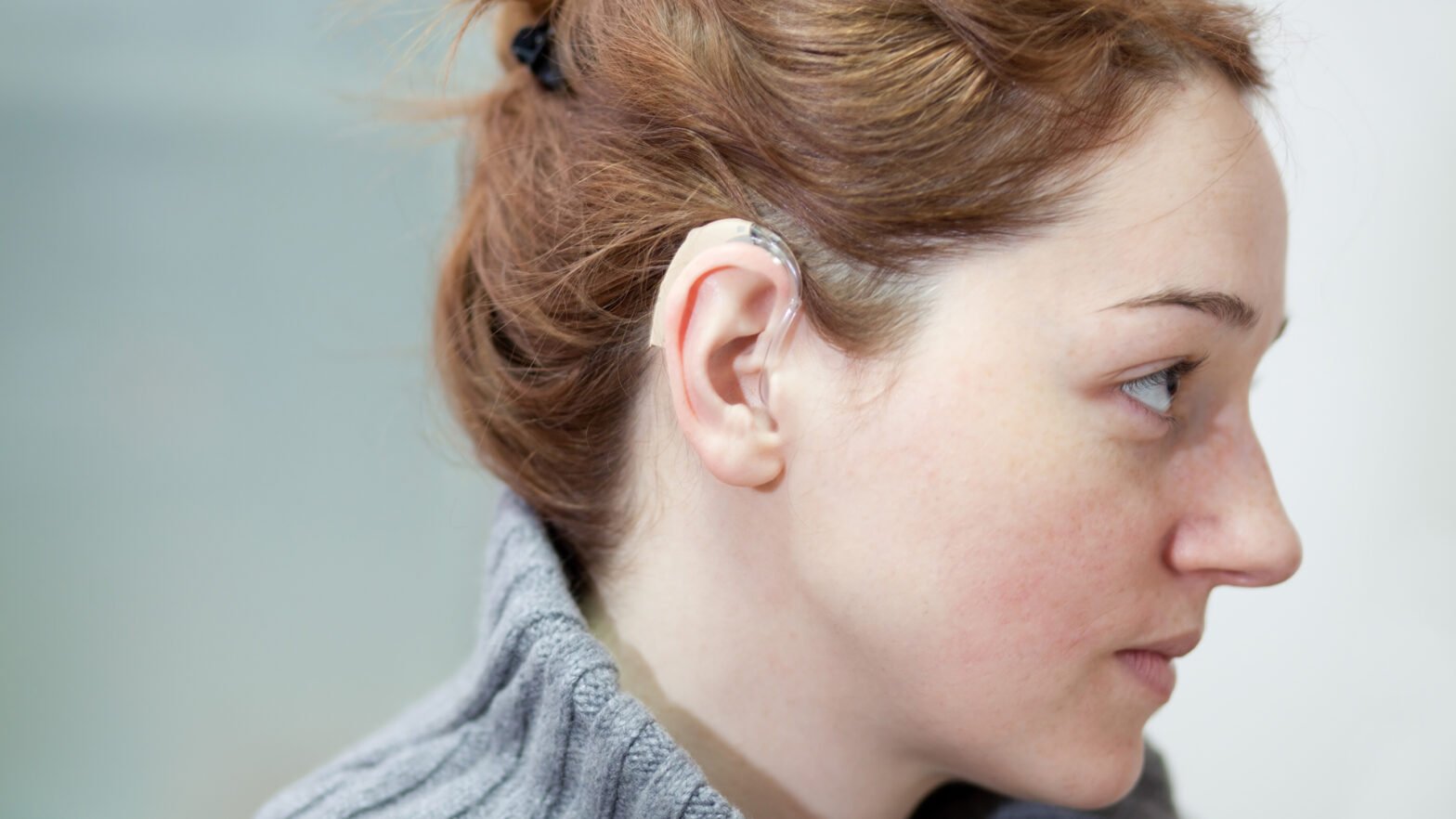 Profile of young woman with a hearing aid
